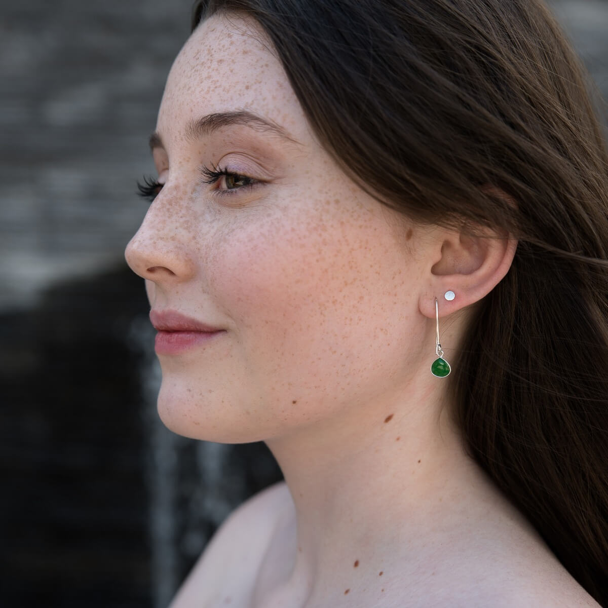 Side view of a girl wearing Teardrop Jade Hoop Earrings, showcasing their elegant design and vibrant green color.