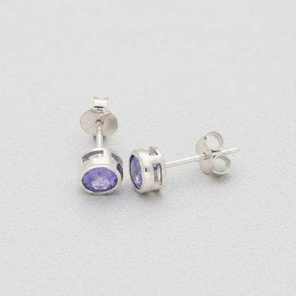 Silver earrings with purple gemstones on a white background